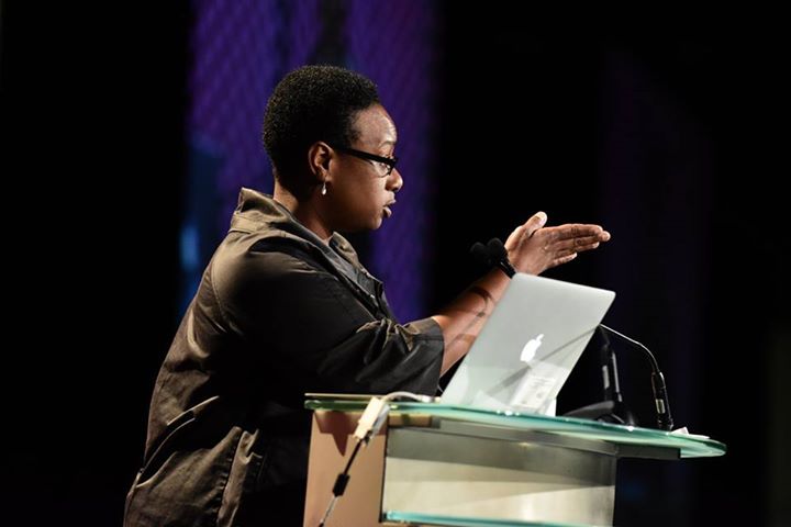 Dr Beronda Montgomery at a Podium speaking to audience